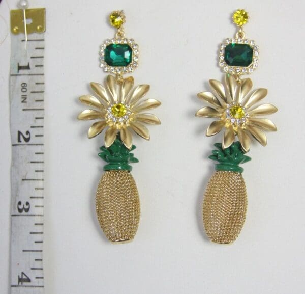 A pair of earrings with gold and green flowers.