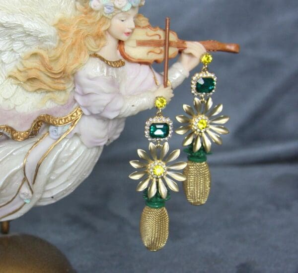 A pair of earrings with flowers and green stones.
