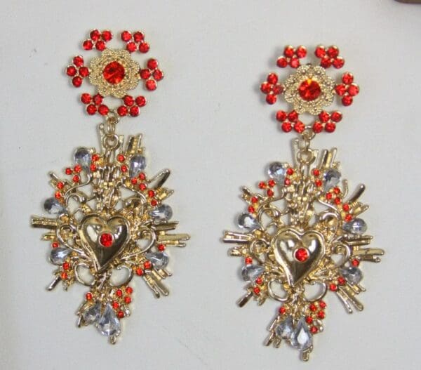A pair of earrings with red and gold accents.