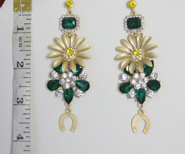 A pair of earrings with green and yellow stones.