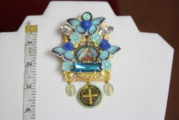 A blue and gold brooch with a cross on it