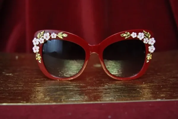 A red pair of sunglasses with flowers on them.