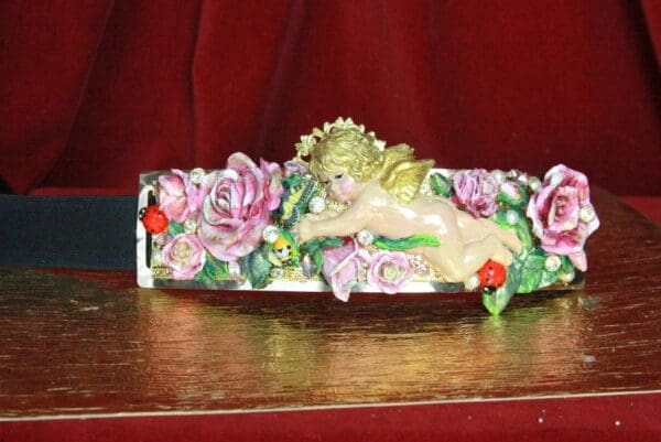 A decorative object with flowers and a cherub on it.
