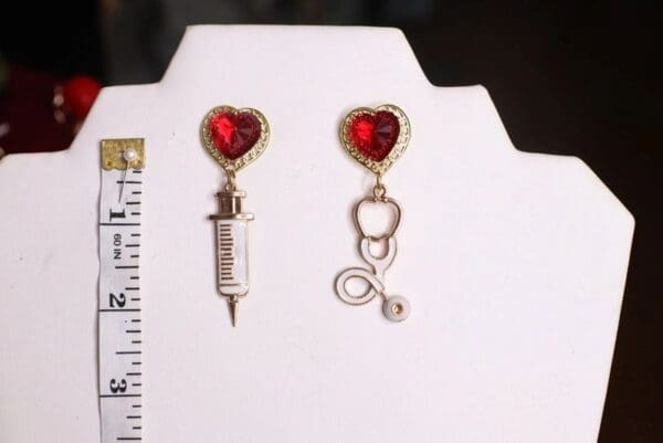 A pair of earrings with a heart and a needle.