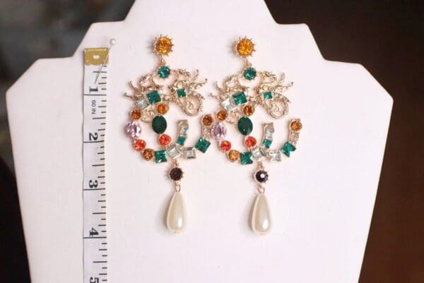 A pair of earrings with pearls and gemstones.