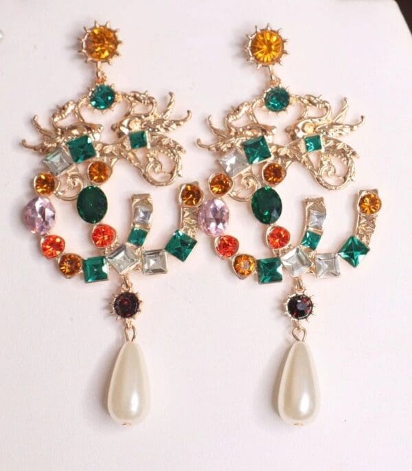 A pair of earrings with colorful stones and pearls.