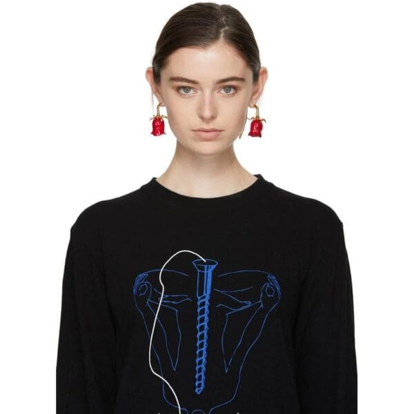A woman wearing red earrings and a black sweater.