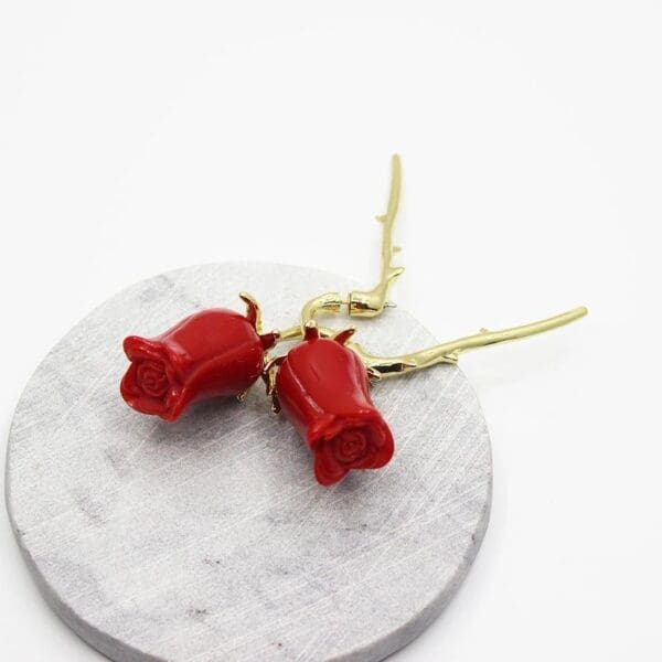 A pair of red roses on top of a white plate.