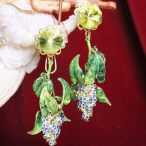 A pair of earrings with green grapes and blue flowers.
