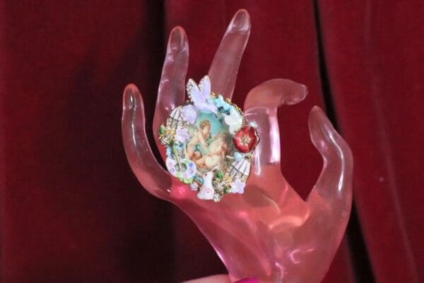 A hand holding a small figurine of fairies.