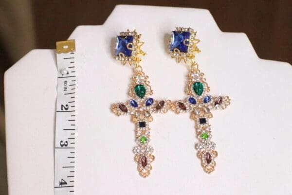 A pair of earrings with cross design and various colored stones.