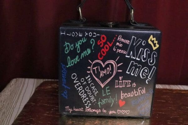A black purse with many different words written on it.