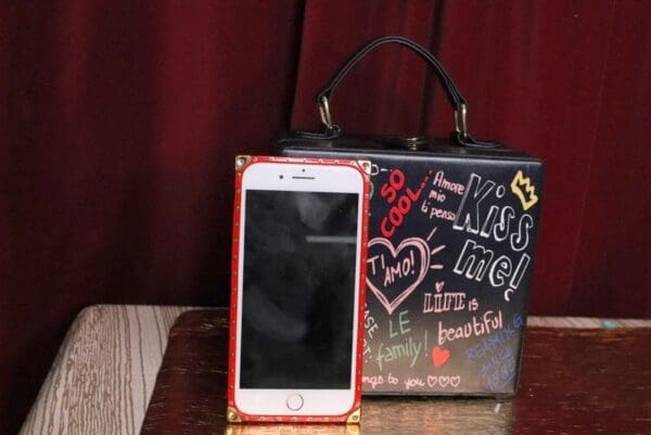 A cell phone sitting on top of a table next to a purse.