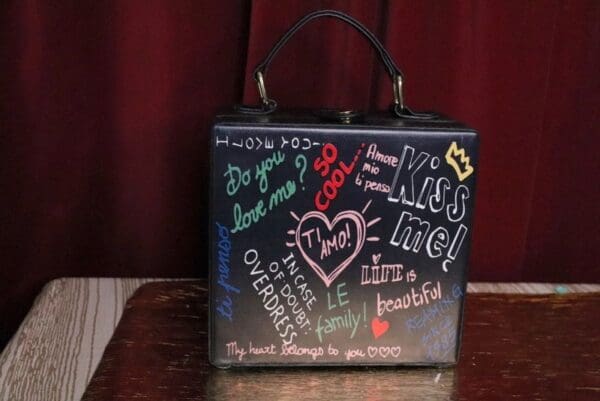 A black purse with writing on it sitting on top of a table.