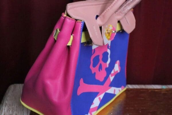A pink purse with a skull and crossbones on it.