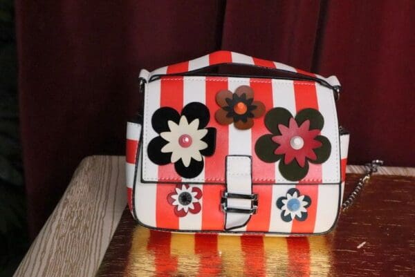 A red and white striped purse with flowers on it.