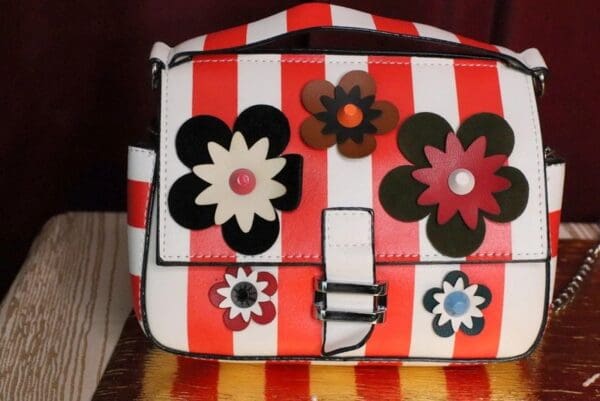 A red and white striped purse with flowers on it.