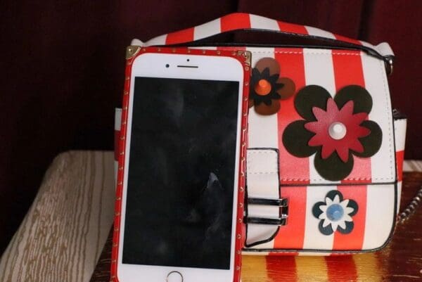 A cell phone sitting on top of a red and white striped bag.
