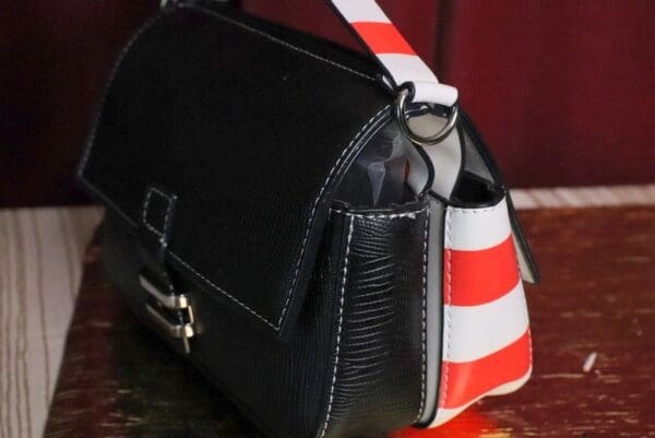 A black purse with red and white stripes on it.