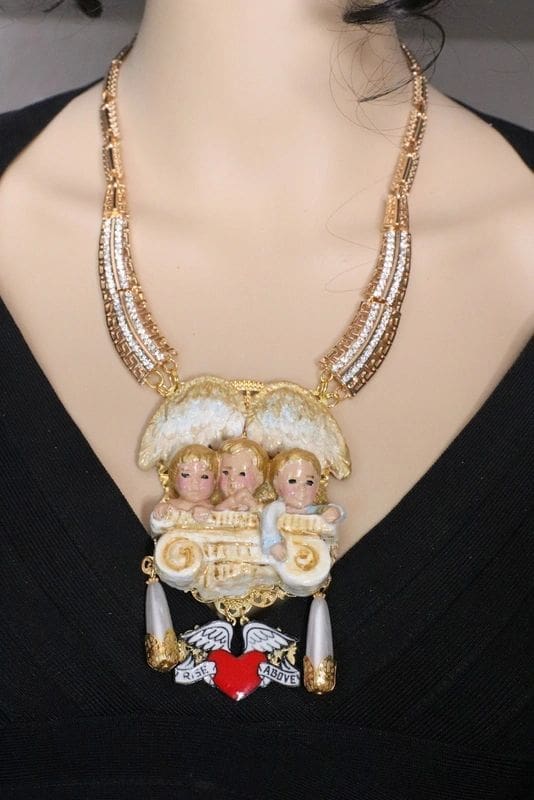 A woman wearing a necklace with three dolls in it.