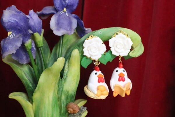 A close up of two earrings hanging on a plant