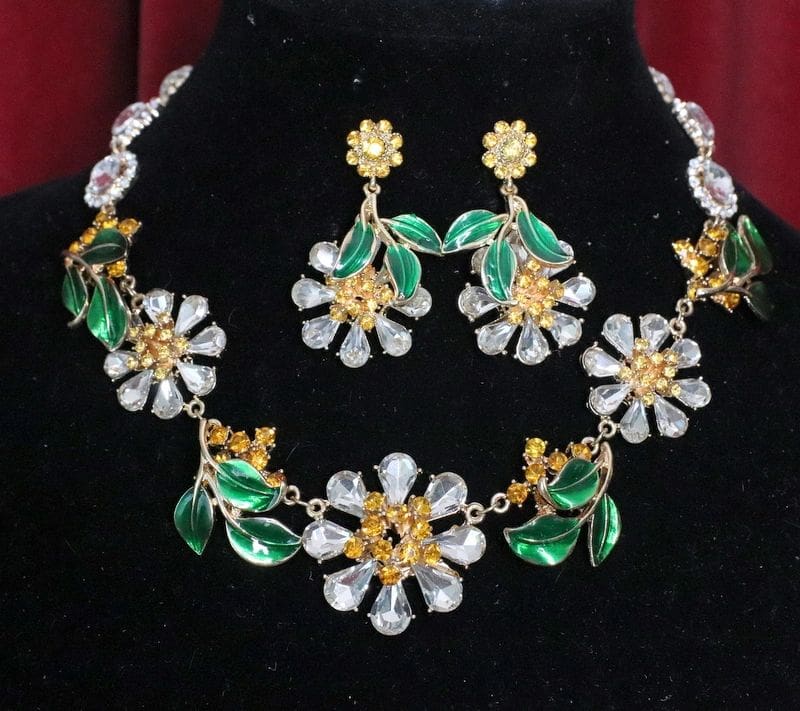 A necklace and earrings set with green flowers.