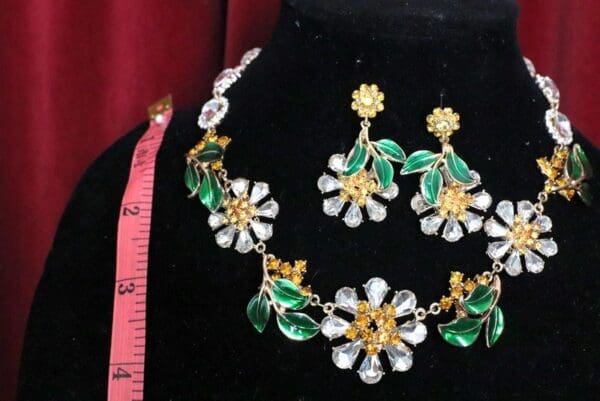 A necklace and earrings set with green flowers.
