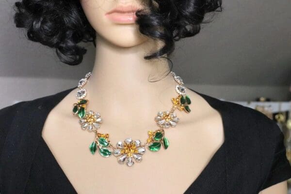 A woman wearing a necklace with green and yellow flowers.