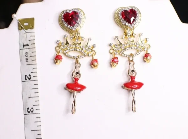 A pair of earrings with red and gold jewelry.