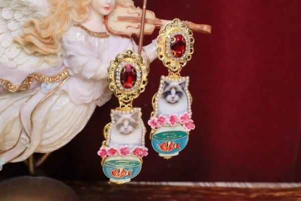 A pair of earrings with cats and roses on them.