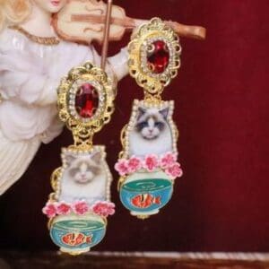 A pair of earrings with cats and roses on them.