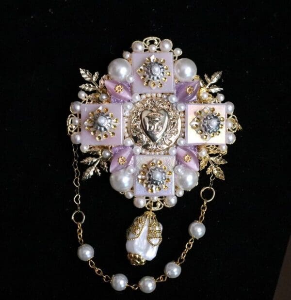 A cross with pearls and a lion head on it.