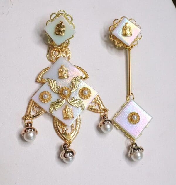 A pair of earrings with gold and white designs.