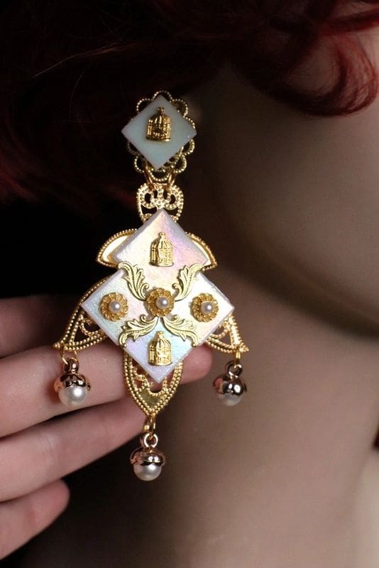 A woman wearing a large white and gold earrings.