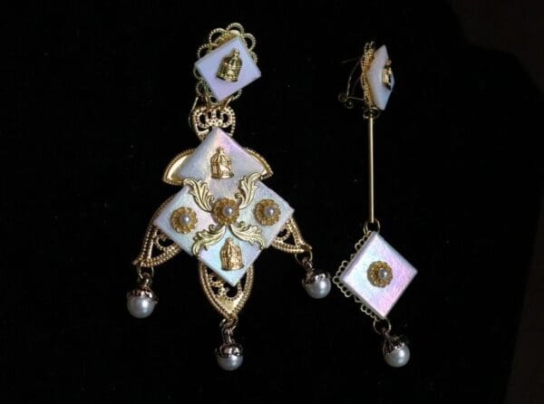 A pair of earrings with gold and white designs.