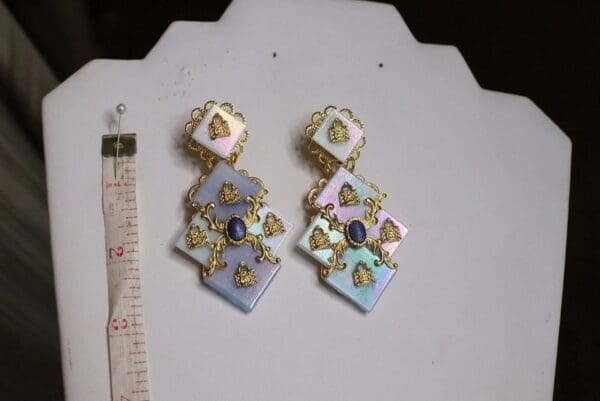 A pair of earrings with gold and blue stones.