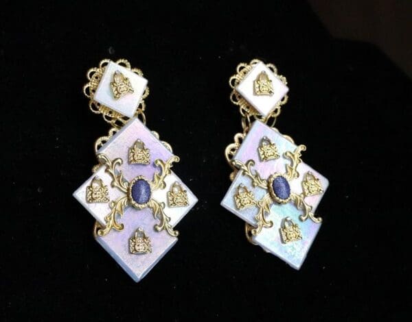 A pair of earrings with gold and white designs.