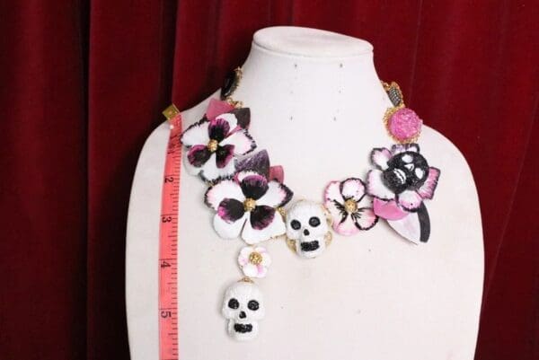 A mannequin wearing a necklace with skulls and flowers.