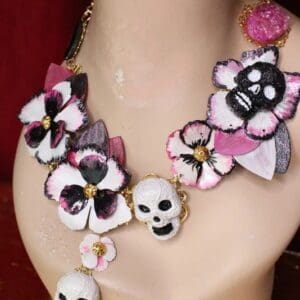 A woman wearing a necklace with skulls and flowers.