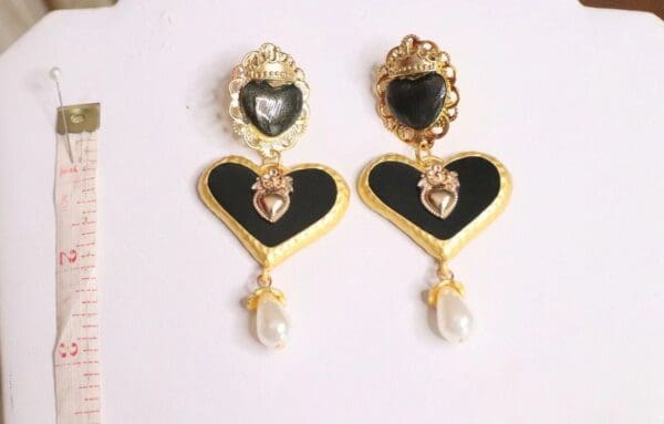 A pair of earrings with black and gold hearts.