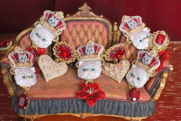 A group of white cats wearing crowns on a couch.