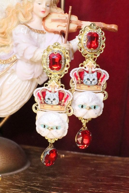 A pair of earrings with cats and red stones.