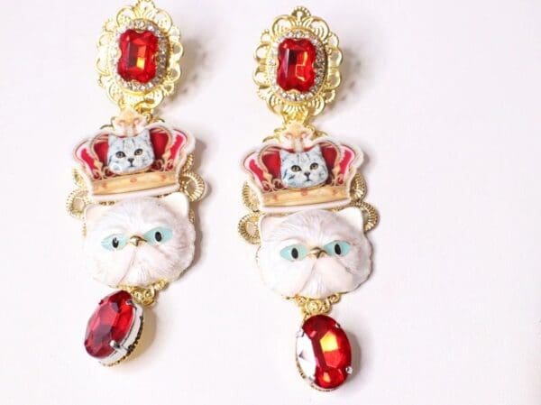 A pair of earrings with cats and red stones.