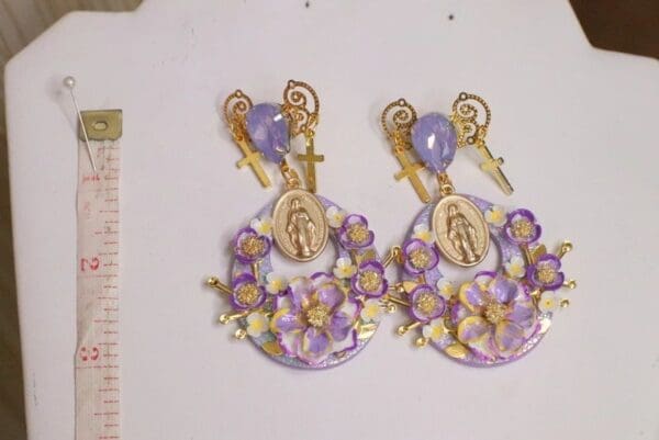 A pair of earrings with purple flowers and gold accents.