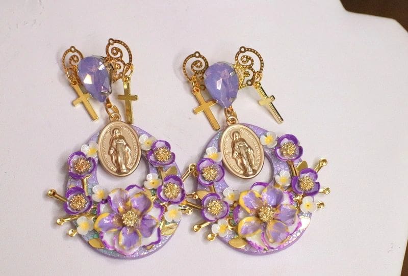 A pair of earrings with purple flowers and key charms.