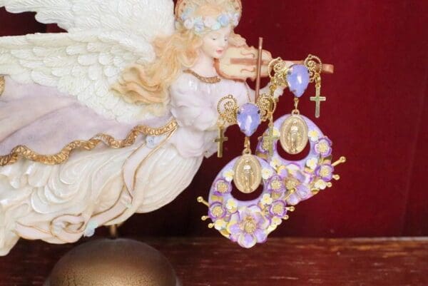 A pair of earrings with crosses and flowers on them.