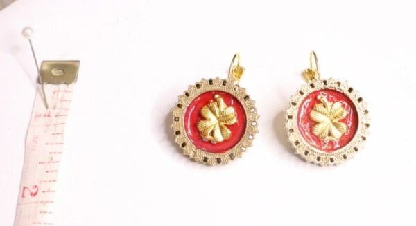 A pair of earrings with red and gold design.