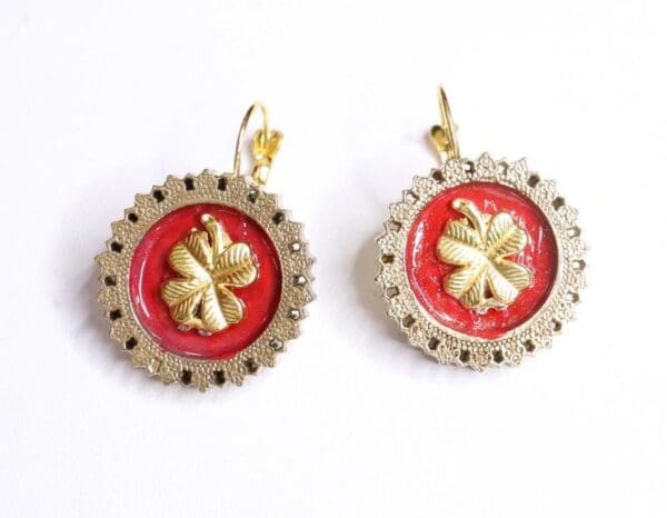 A pair of earrings with red and gold flowers.