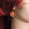 A woman with red hair wearing earrings.