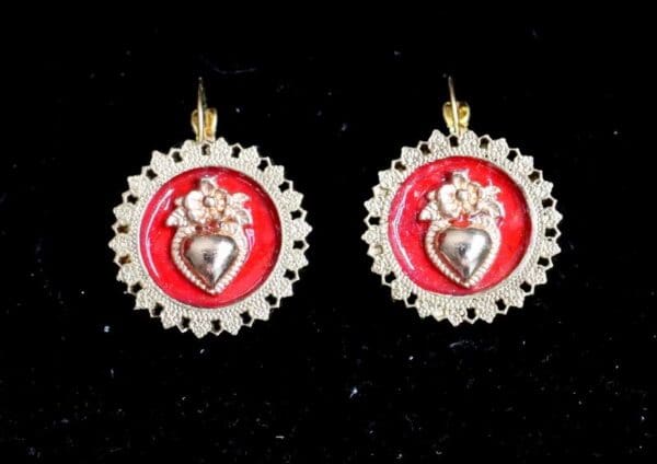 A pair of earrings with a heart on it.